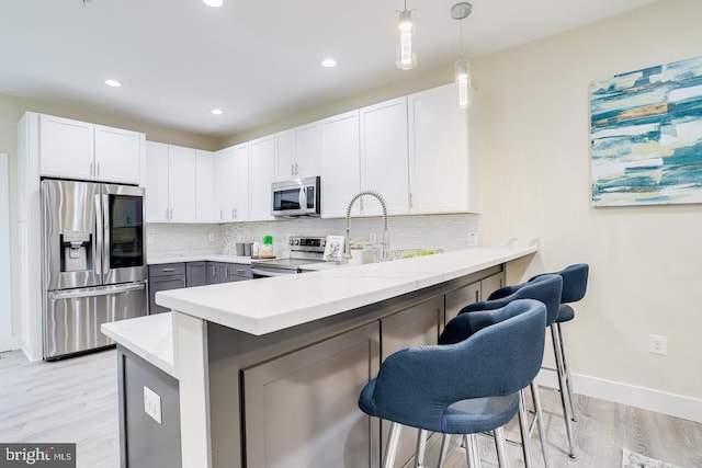 2405 Naylor Rd SE, Washington, DC 20020 - kitchen with appliances with stainless steel finishes, a peninsula, light wood-style floors, backsplash, and a kitchen breakfast bar