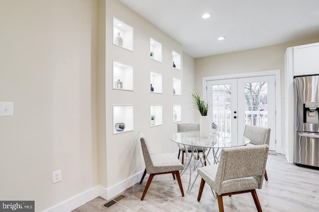 dining space with french doors and light hardwood / wood-style flooring