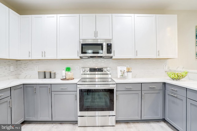 kitchen featuring gray cabinets, white cabinetry, light hardwood / wood-style floors, and appliances with stainless steel finishes