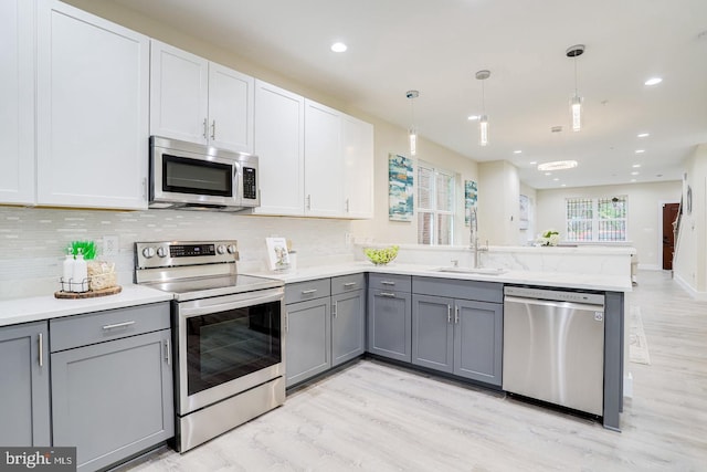 kitchen with white cabinets, appliances with stainless steel finishes, decorative light fixtures, and gray cabinetry