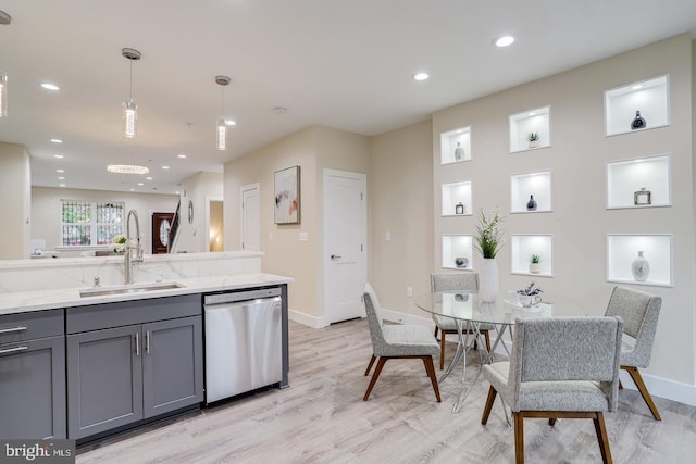 kitchen featuring decorative light fixtures, gray cabinets, sink, light hardwood / wood-style floors, and stainless steel dishwasher