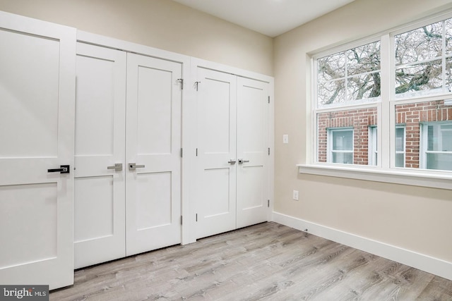 unfurnished bedroom with multiple closets and light wood-type flooring