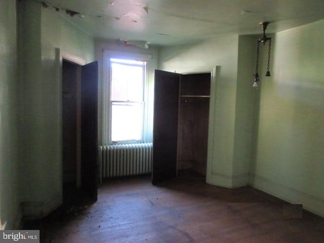 unfurnished bedroom featuring radiator heating unit and hardwood / wood-style flooring