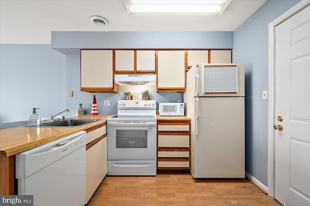 kitchen with white cabinetry, sink, light hardwood / wood-style floors, and white appliances