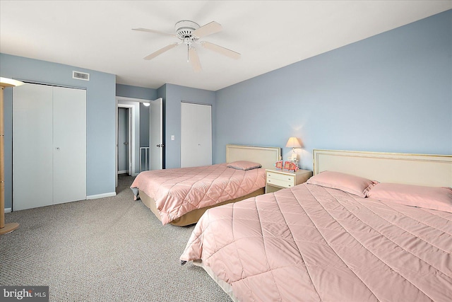 bedroom with carpet, ceiling fan, and two closets