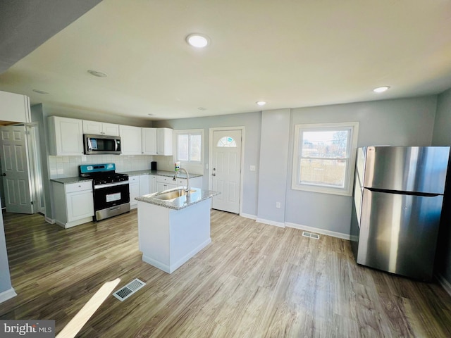 kitchen featuring light stone countertops, backsplash, stainless steel appliances, sink, and white cabinetry