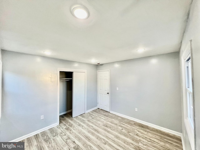 unfurnished bedroom with light wood-type flooring and a closet