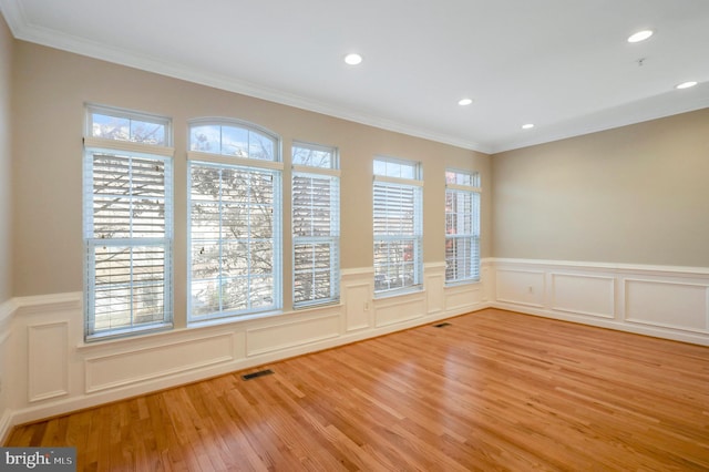 unfurnished room featuring a healthy amount of sunlight, light hardwood / wood-style floors, and crown molding