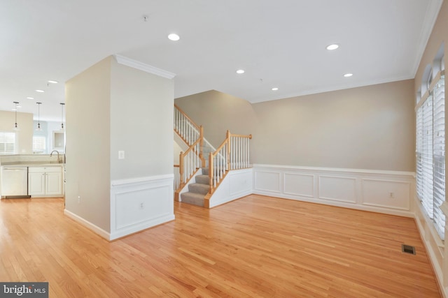 unfurnished room featuring a wealth of natural light, crown molding, light hardwood / wood-style floors, and sink