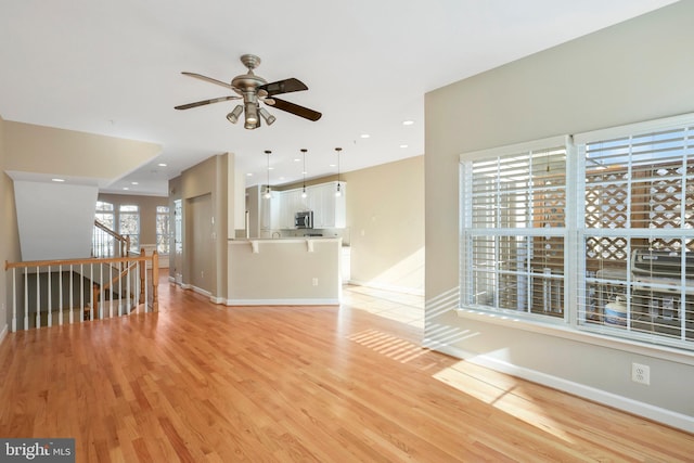 unfurnished living room featuring ceiling fan and light wood-type flooring