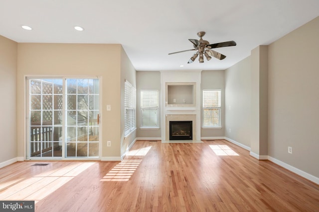 unfurnished living room with light hardwood / wood-style flooring, ceiling fan, and a healthy amount of sunlight