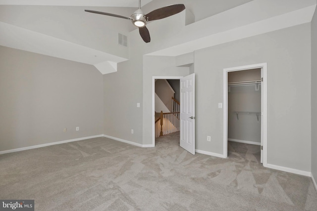 unfurnished bedroom with a walk in closet, ceiling fan, a closet, and light colored carpet