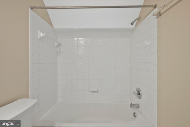 bathroom featuring tiled shower / bath combo and toilet