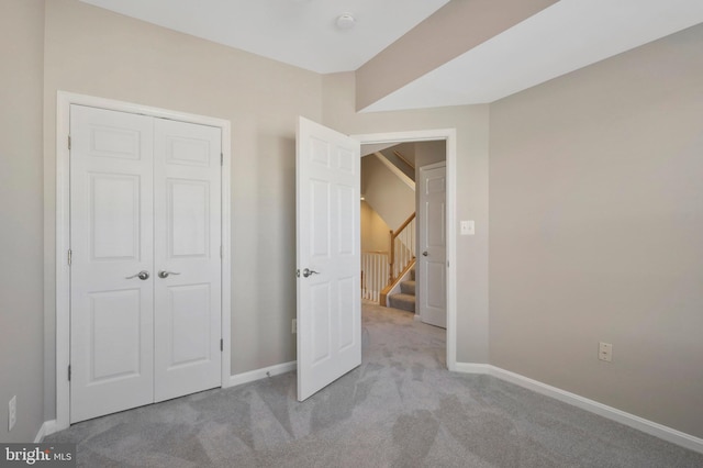 unfurnished bedroom with light carpet and a closet