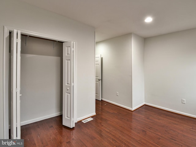 unfurnished bedroom featuring dark wood-type flooring and a closet