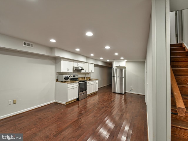 kitchen featuring dark hardwood / wood-style floors, white cabinetry, appliances with stainless steel finishes, and dark stone counters