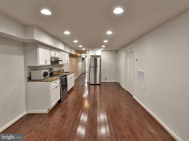 kitchen with dark stone counters, white cabinets, sink, dark hardwood / wood-style flooring, and stainless steel appliances