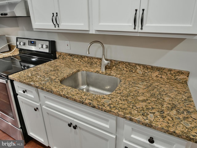 kitchen with sink, ventilation hood, dark stone countertops, electric stove, and white cabinets