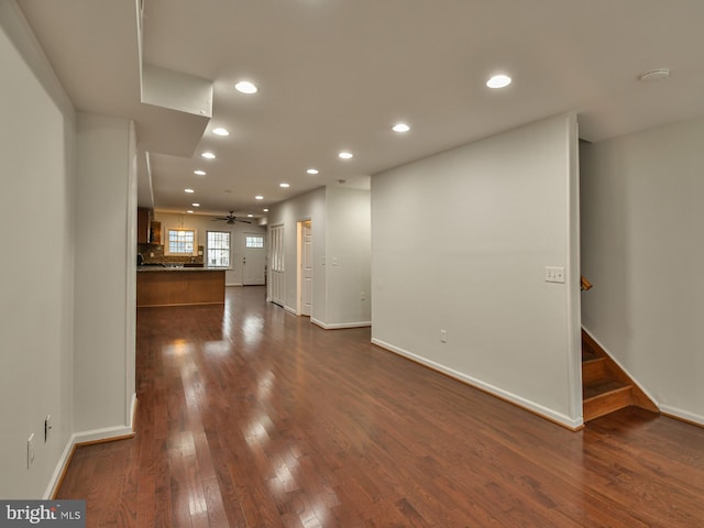 unfurnished living room featuring ceiling fan and dark wood-type flooring