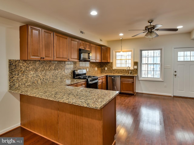 kitchen with black appliances, hanging light fixtures, tasteful backsplash, dark hardwood / wood-style flooring, and kitchen peninsula