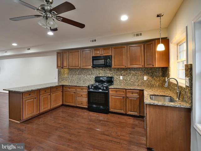 kitchen featuring light stone countertops, sink, dark wood-type flooring, decorative light fixtures, and black appliances