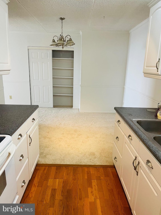 kitchen with a textured ceiling, dark hardwood / wood-style floors, white cabinetry, and hanging light fixtures