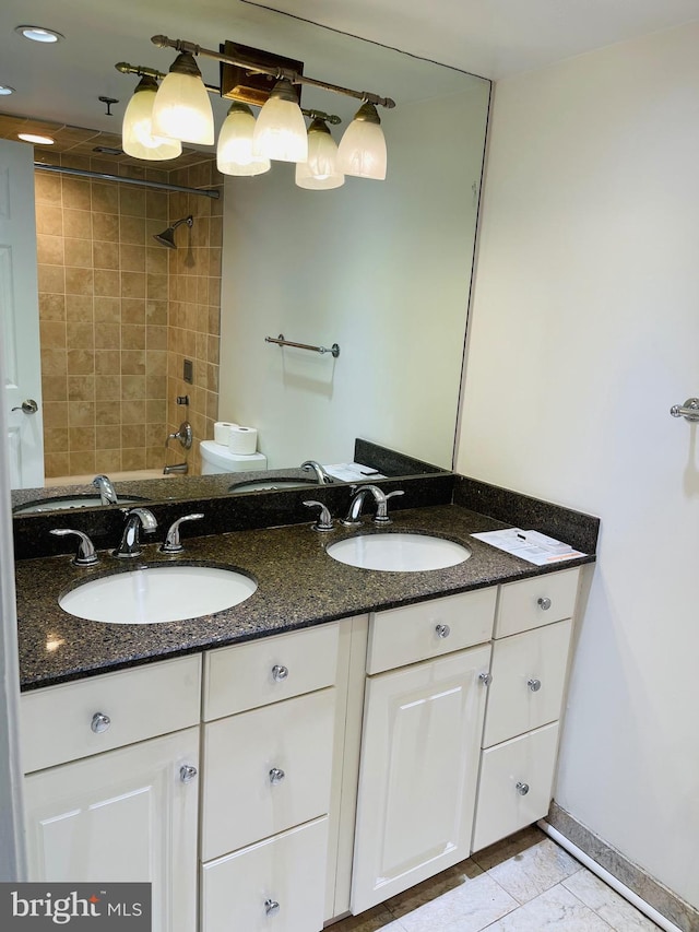 bathroom with a tile shower, vanity, and toilet