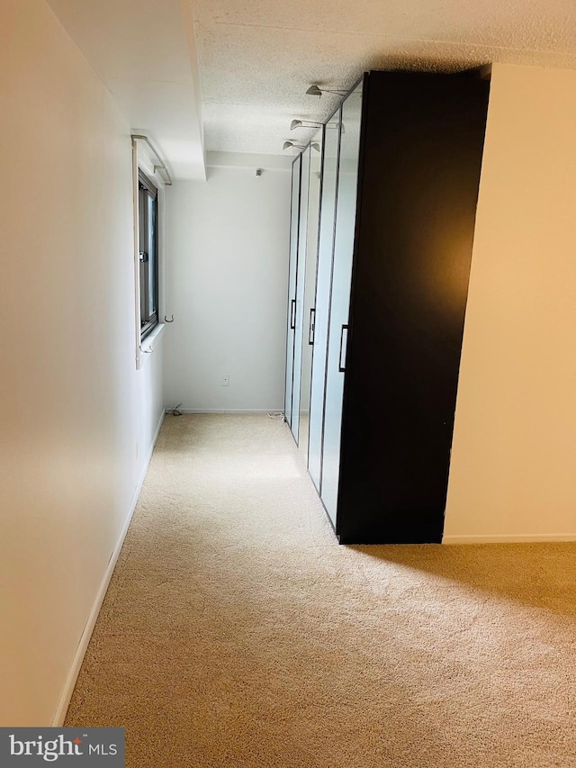 hall featuring carpet flooring and a textured ceiling