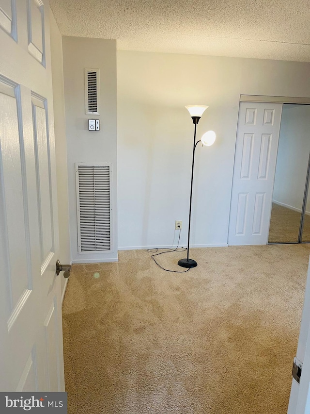 carpeted empty room with a textured ceiling