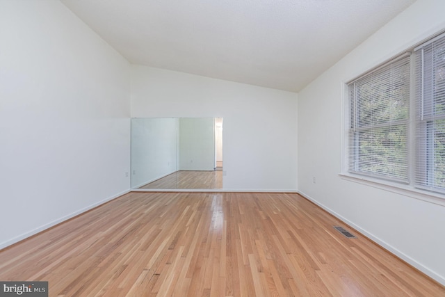 empty room with light hardwood / wood-style flooring and lofted ceiling