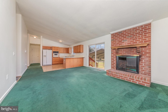 unfurnished living room with a textured ceiling, dark colored carpet, vaulted ceiling, and a brick fireplace