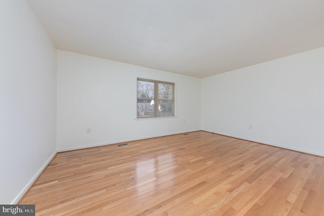 unfurnished room with a textured ceiling and light wood-type flooring