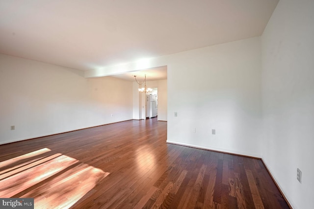 empty room featuring a chandelier and dark hardwood / wood-style flooring