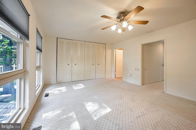 unfurnished bedroom with a closet, light colored carpet, and ceiling fan