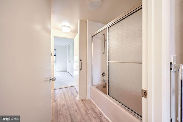 bathroom with hardwood / wood-style floors and bath / shower combo with glass door