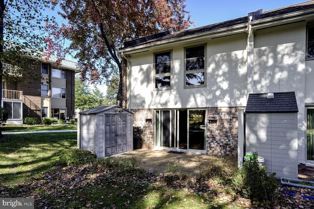 rear view of property featuring a lawn, a balcony, and a storage shed