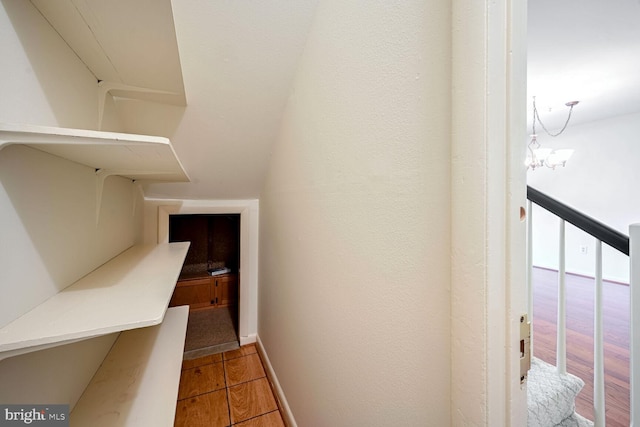 staircase with hardwood / wood-style floors and an inviting chandelier