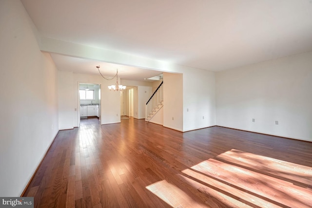 unfurnished living room with dark wood-type flooring and a chandelier