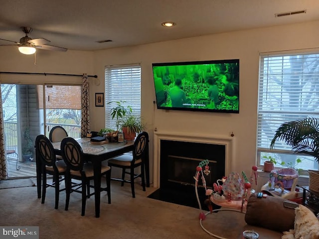 carpeted dining space with ceiling fan