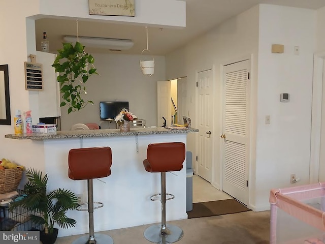 kitchen with kitchen peninsula, light stone counters, and a breakfast bar area