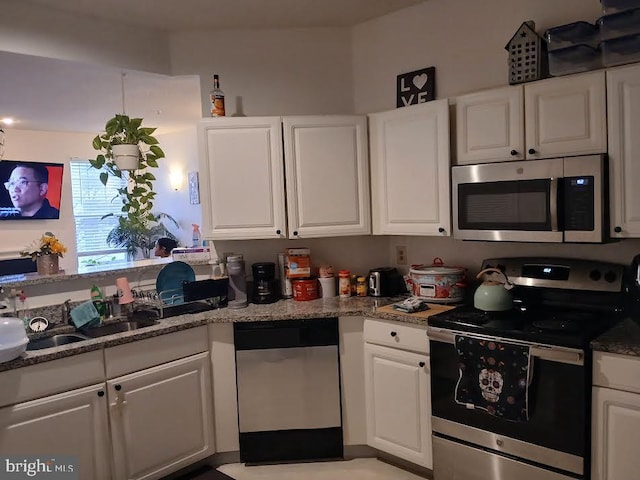 kitchen featuring sink, white cabinetry, stainless steel appliances, and dark stone counters