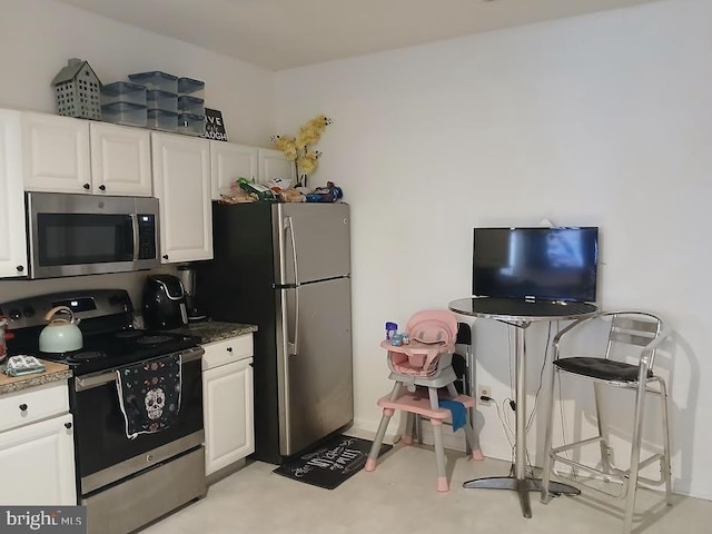 kitchen with light colored carpet, white cabinetry, dark stone countertops, and appliances with stainless steel finishes