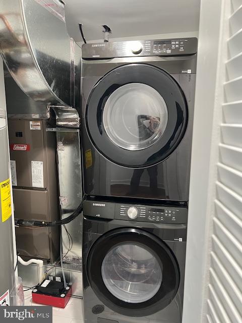 washroom featuring stacked washer and dryer and tile patterned flooring