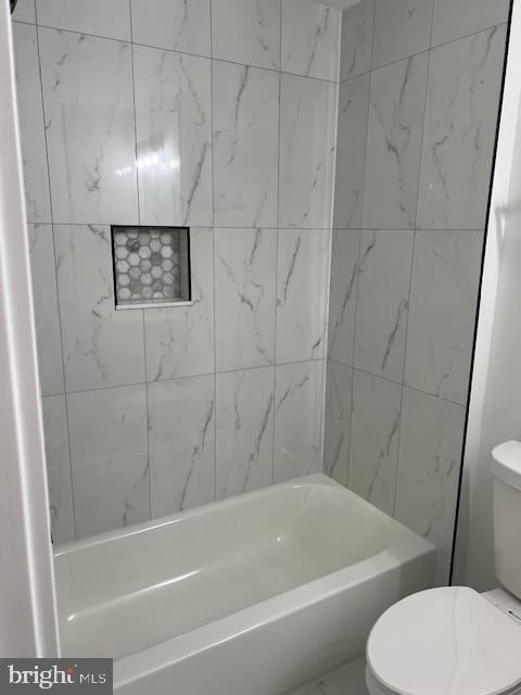 bathroom featuring tiled shower / bath and toilet