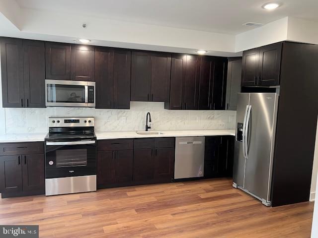 kitchen with light hardwood / wood-style flooring, dark brown cabinets, and stainless steel appliances