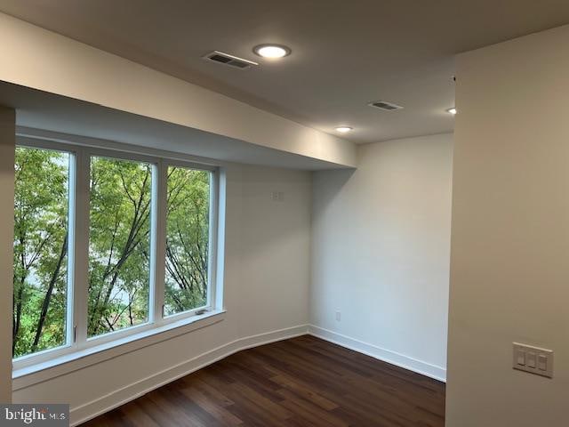 basement with a wealth of natural light and dark hardwood / wood-style floors