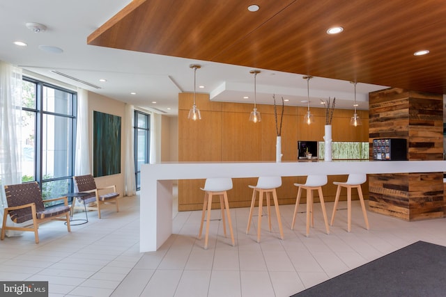 kitchen featuring a kitchen breakfast bar, wood ceiling, light tile patterned floors, and decorative light fixtures