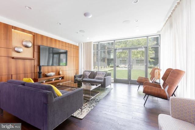 living room featuring dark hardwood / wood-style flooring, expansive windows, wooden walls, and french doors