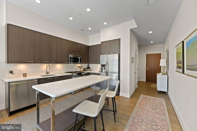 kitchen featuring stainless steel appliances, sink, light hardwood / wood-style flooring, and dark brown cabinetry