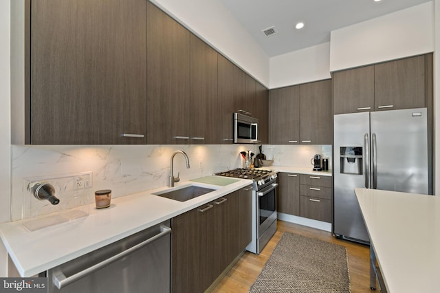 kitchen with tasteful backsplash, light wood-type flooring, sink, and stainless steel appliances